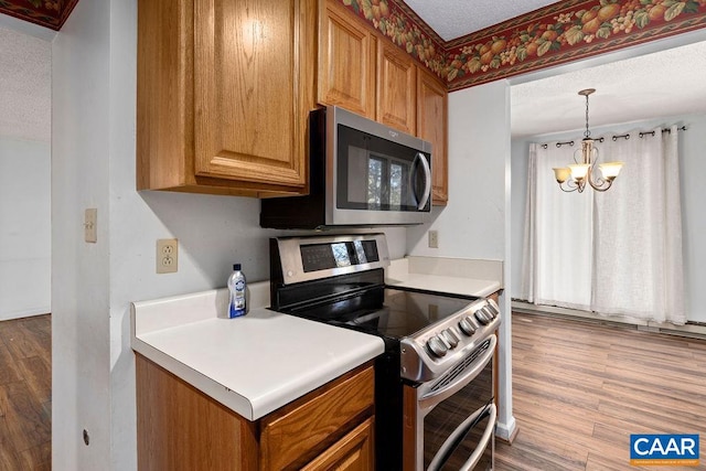 kitchen with a notable chandelier, light hardwood / wood-style floors, stainless steel appliances, and a textured ceiling