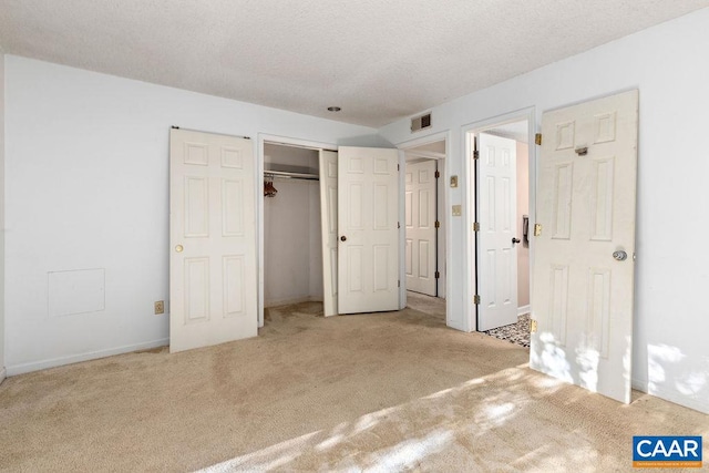 unfurnished bedroom featuring light carpet, a closet, and a textured ceiling