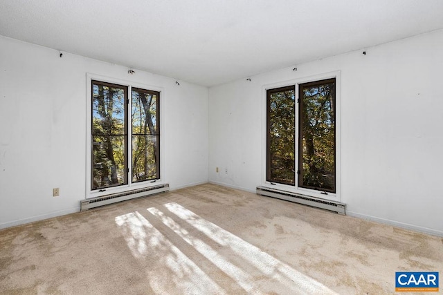 spare room featuring light carpet, a wealth of natural light, and a baseboard radiator