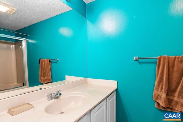 bathroom featuring vanity, a shower, and a textured ceiling