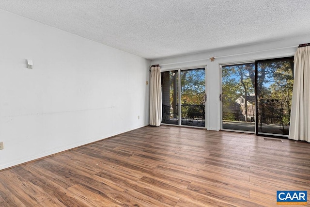 spare room featuring wood-type flooring and a textured ceiling