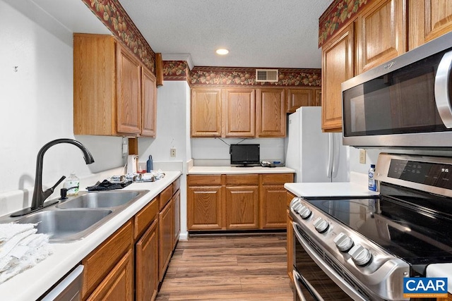 kitchen with stainless steel appliances, hardwood / wood-style flooring, a textured ceiling, and sink