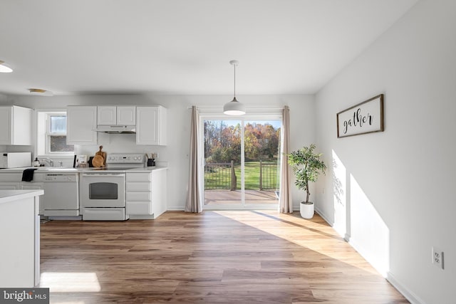 kitchen with white cabinets, decorative light fixtures, white appliances, and light hardwood / wood-style floors