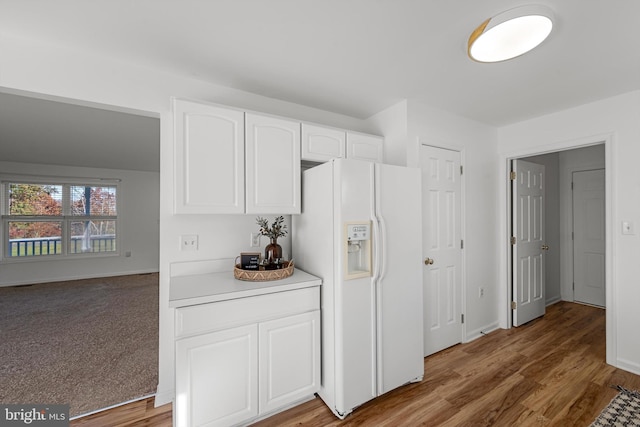 kitchen featuring white cabinetry, white fridge with ice dispenser, and hardwood / wood-style flooring