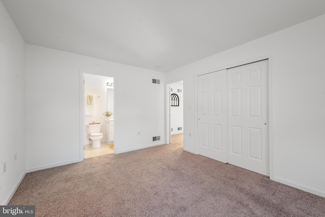 unfurnished bedroom featuring carpet flooring, a closet, and ensuite bath