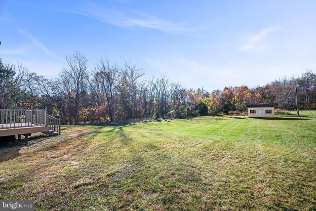 view of yard featuring a wooden deck and a storage unit