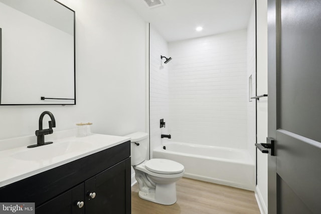 full bathroom featuring hardwood / wood-style floors, vanity, toilet, and tiled shower / bath