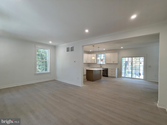 unfurnished living room with hardwood / wood-style flooring, ornamental molding, and a healthy amount of sunlight