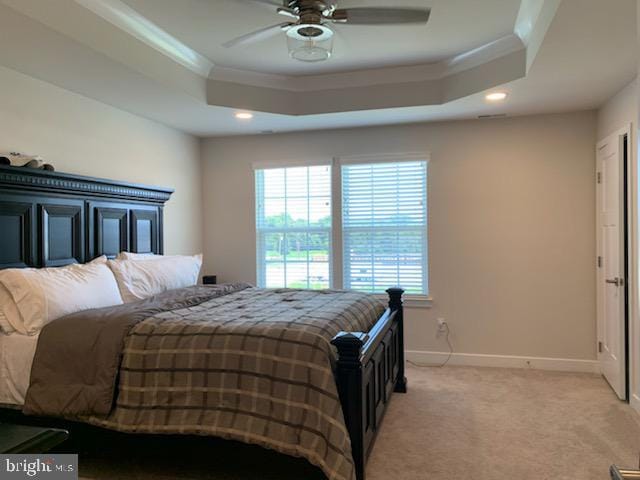 carpeted bedroom featuring ceiling fan, a tray ceiling, and crown molding