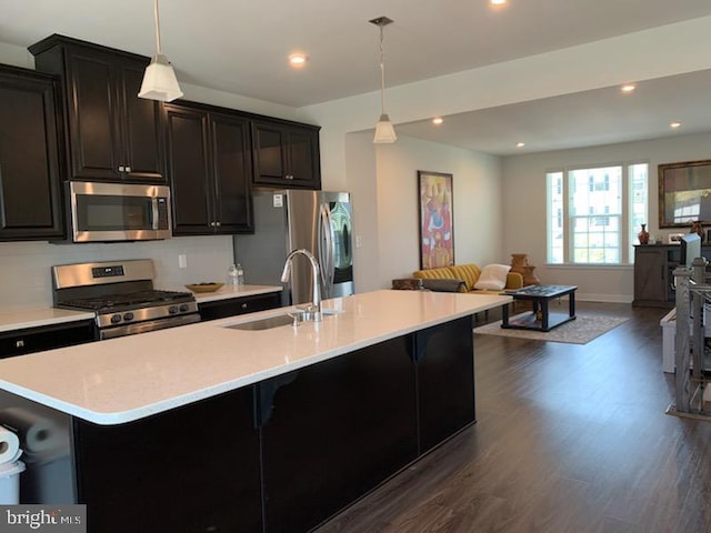 kitchen featuring stainless steel appliances, dark wood-type flooring, sink, pendant lighting, and a kitchen bar