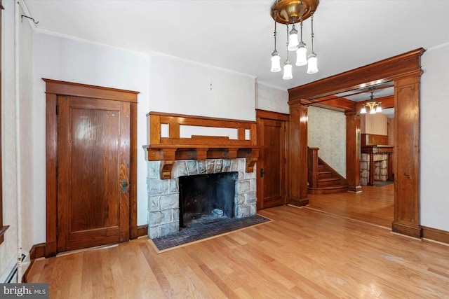 unfurnished living room featuring baseboards, light wood-type flooring, ornamental molding, a fireplace, and stairs