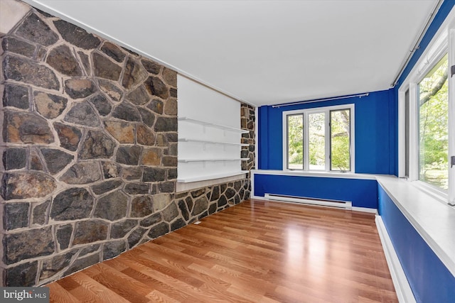empty room with baseboard heating and wood finished floors