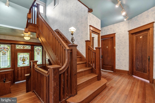 stairs with visible vents, track lighting, baseboards, hardwood / wood-style flooring, and wallpapered walls