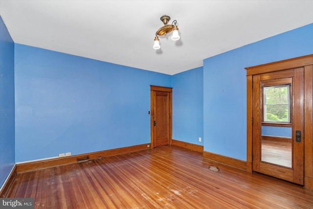 spare room featuring baseboards and wood finished floors