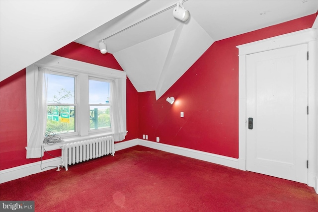 additional living space with carpet flooring, baseboards, radiator, and lofted ceiling