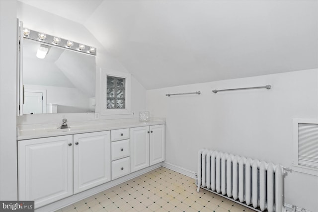 bathroom with radiator heating unit, tile patterned floors, vanity, and lofted ceiling