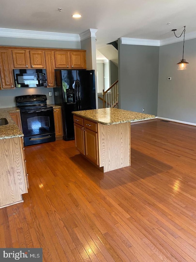 kitchen featuring hanging light fixtures, black appliances, a center island, and dark hardwood / wood-style flooring