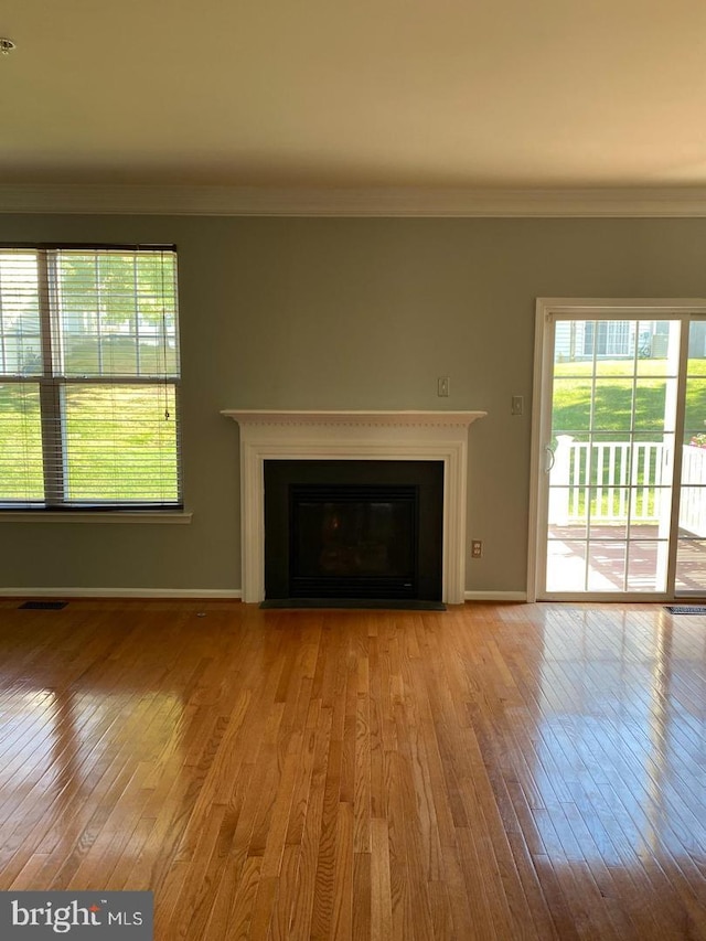 unfurnished living room featuring crown molding and light wood-type flooring