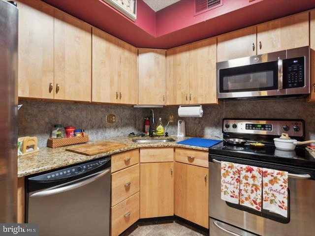 kitchen featuring light brown cabinets, sink, tasteful backsplash, light stone counters, and stainless steel appliances