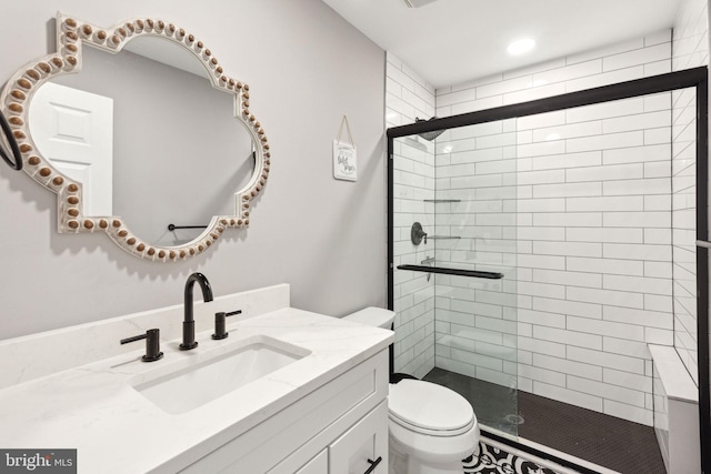 bathroom with a shower with door, vanity, and toilet