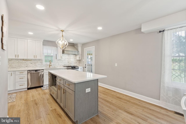 kitchen featuring a kitchen island, sink, hanging light fixtures, appliances with stainless steel finishes, and premium range hood