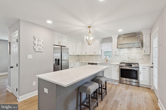 kitchen with light hardwood / wood-style floors, sink, stainless steel appliances, custom exhaust hood, and white cabinetry