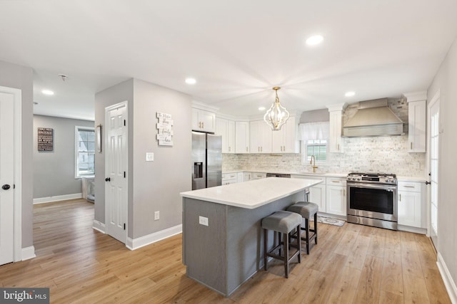 kitchen featuring premium range hood, a kitchen island, white cabinetry, stainless steel appliances, and light hardwood / wood-style floors