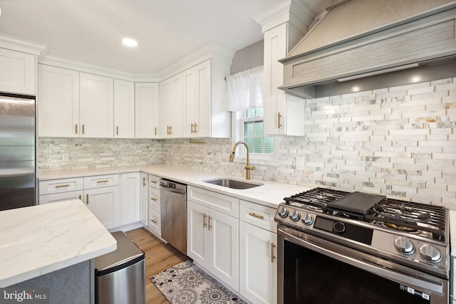 kitchen featuring light wood-type flooring, tasteful backsplash, sink, white cabinets, and appliances with stainless steel finishes