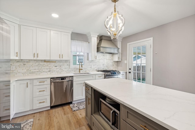 kitchen with white cabinets, pendant lighting, light hardwood / wood-style flooring, appliances with stainless steel finishes, and custom range hood