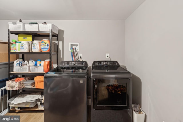 clothes washing area with hardwood / wood-style floors and washing machine and dryer