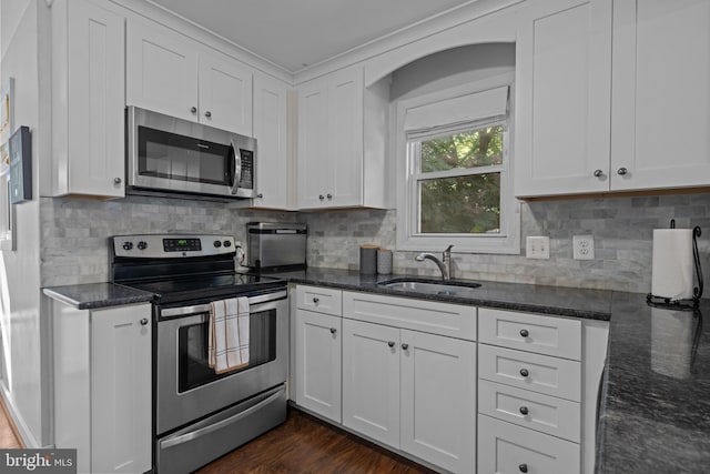kitchen featuring stainless steel appliances, a sink, white cabinets, and dark stone countertops