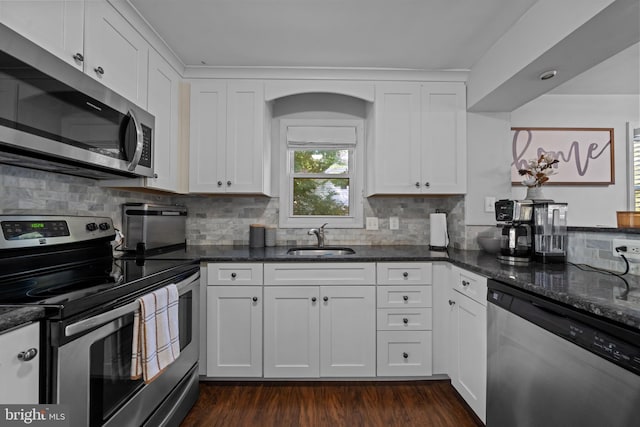 kitchen featuring stainless steel appliances, a sink, dark stone countertops, and decorative backsplash
