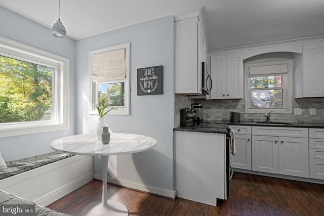 kitchen with a sink, tasteful backsplash, dark wood-style flooring, baseboards, and stainless steel appliances