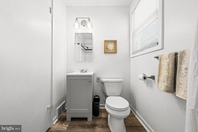 bathroom featuring wood finished floors, toilet, vanity, and baseboards
