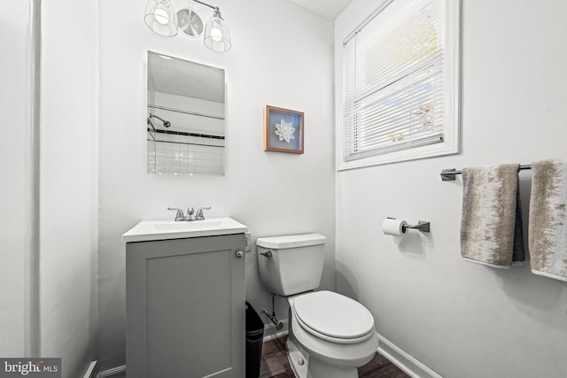 bathroom with toilet, wood finished floors, vanity, and baseboards