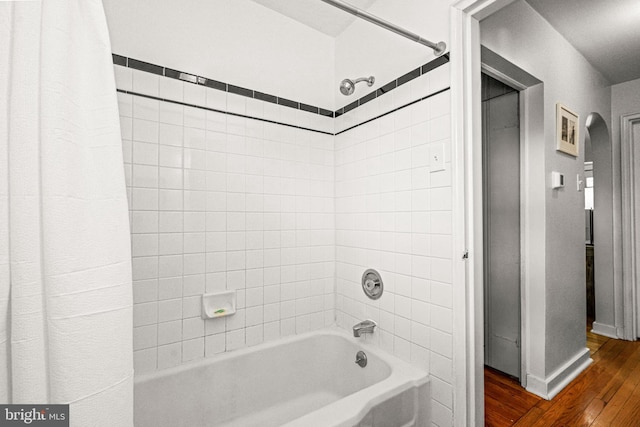 full bath with shower / bath combo, wood finished floors, and baseboards