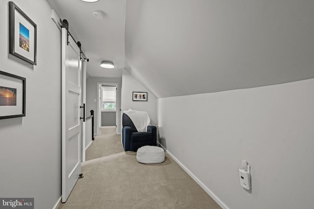 living area with carpet flooring, a barn door, vaulted ceiling, and baseboards