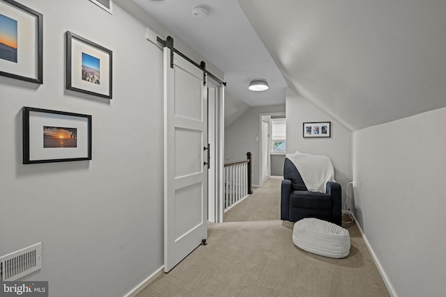 living area with light carpet, baseboards, lofted ceiling, a barn door, and an upstairs landing