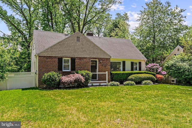 new england style home featuring a chimney, brick siding, and roof with shingles