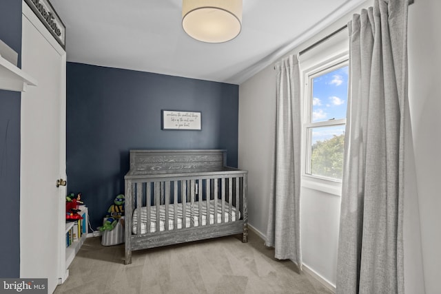 carpeted bedroom with a crib and baseboards