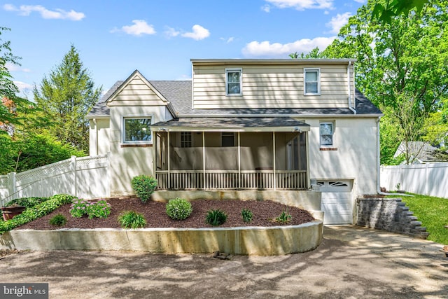 rear view of house featuring a sunroom, a shingled roof, fence, and an attached garage