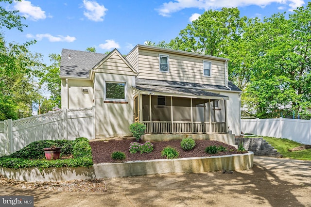 view of front of house featuring a sunroom, a shingled roof, and fence