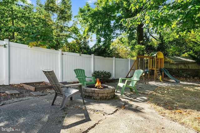 view of patio featuring a fire pit, fence, and a playground