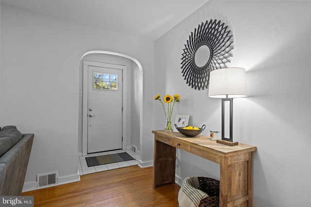 entrance foyer with arched walkways, wood finished floors, and baseboards