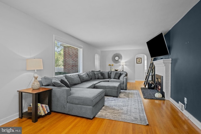 living area with a fireplace, wood finished floors, and baseboards