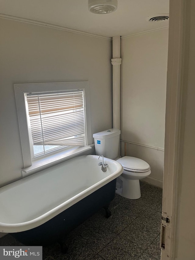 bathroom with a tub to relax in and toilet