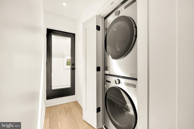 clothes washing area featuring stacked washer / dryer and light hardwood / wood-style floors