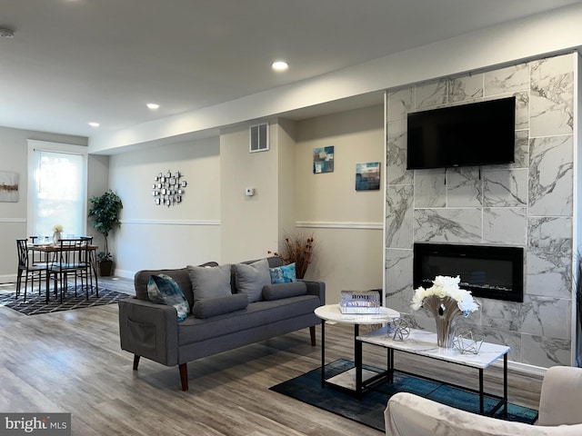 living room featuring wood-type flooring, tile walls, and a premium fireplace