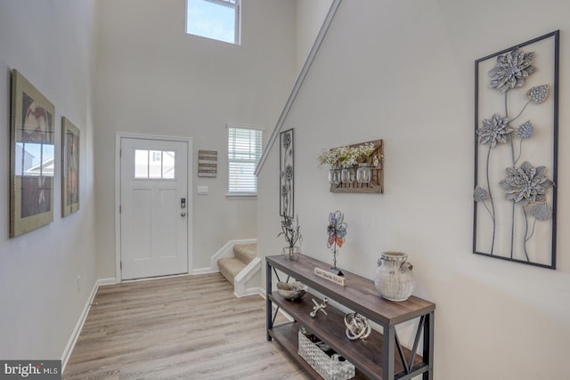 entryway featuring a towering ceiling and light wood-type flooring