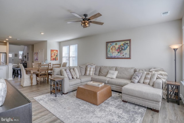 living room with light hardwood / wood-style floors and ceiling fan